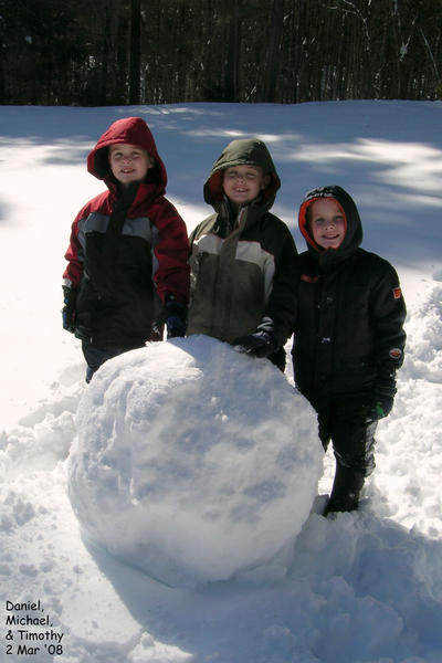 All three boys working on a snowman