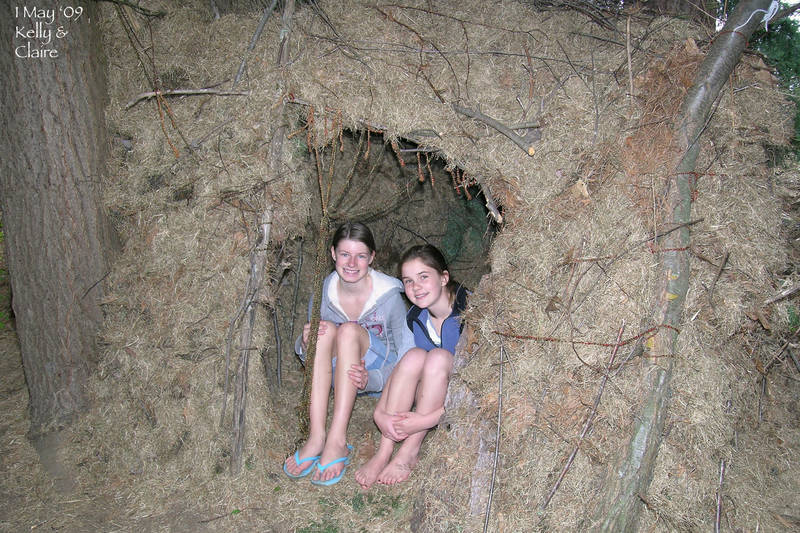 Kelly and Claire build a little house out of twigs and thatch