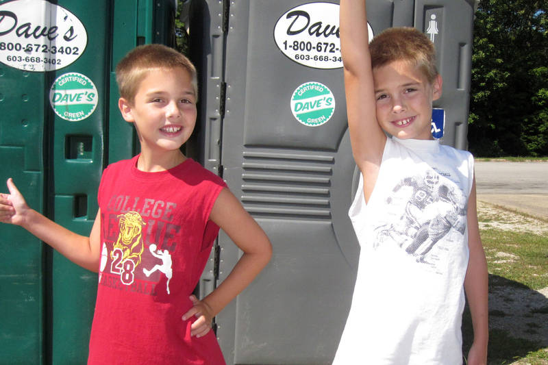 Daniel and Michael pose in front of Porta-Potties